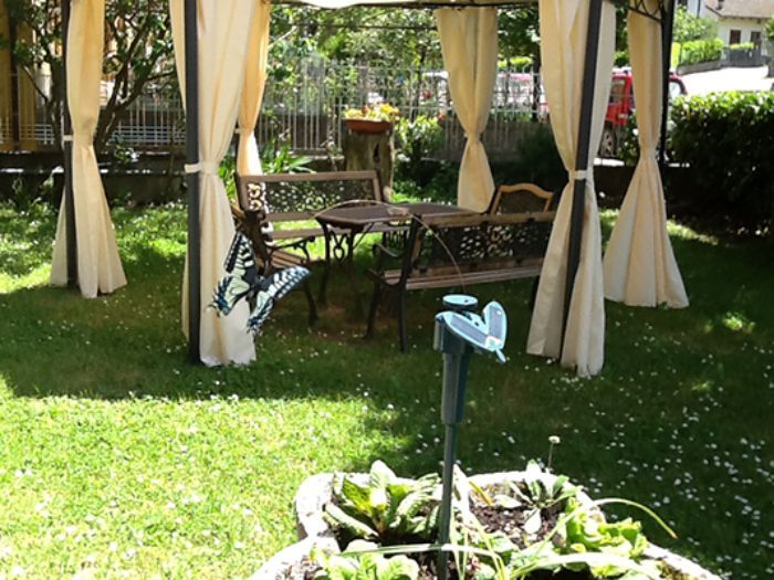 Un giardino con gazebo, tavolo e sedie