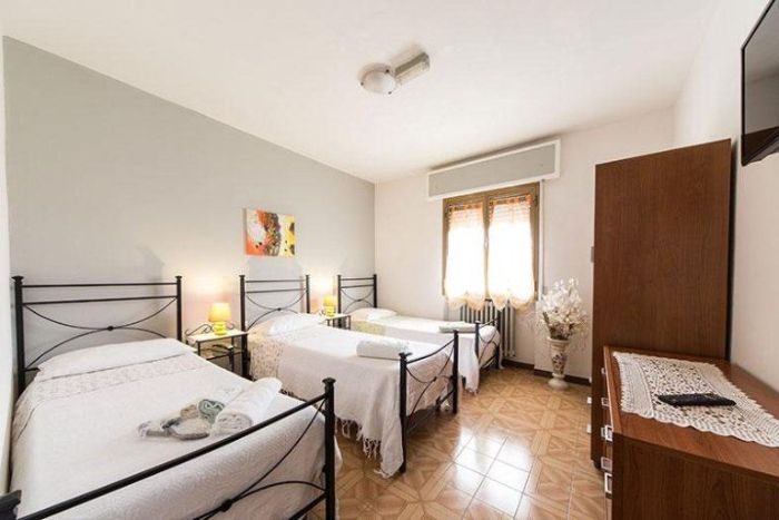 Una camera da letto con tre letti e una TV a schermo piatto