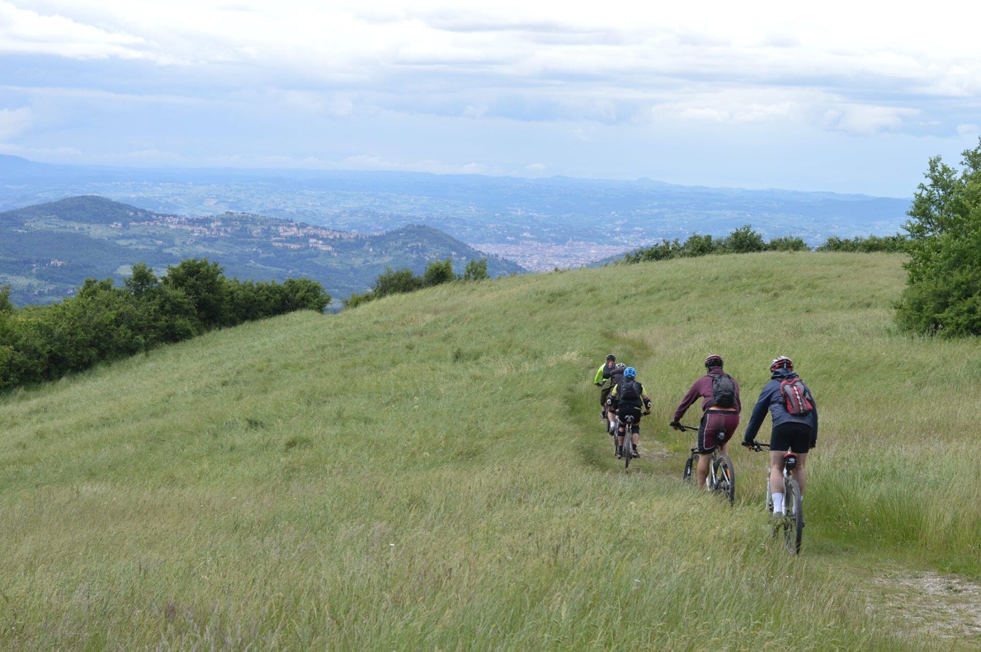 Un gruppo di persone sta andando in bicicletta giù per una collina erbosa.