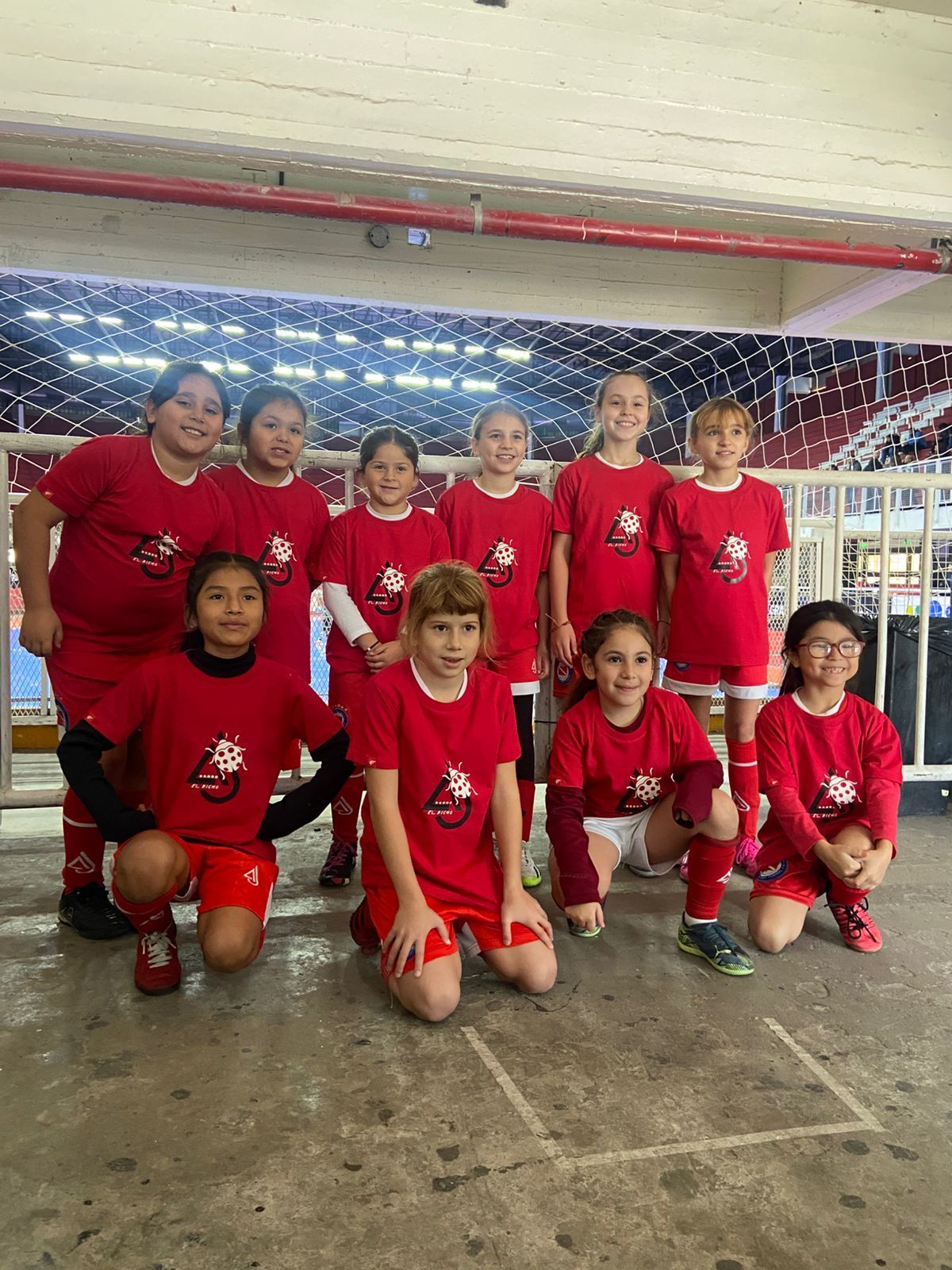 Equipo de fútbol juvenil con camisetas rojas, en interior.