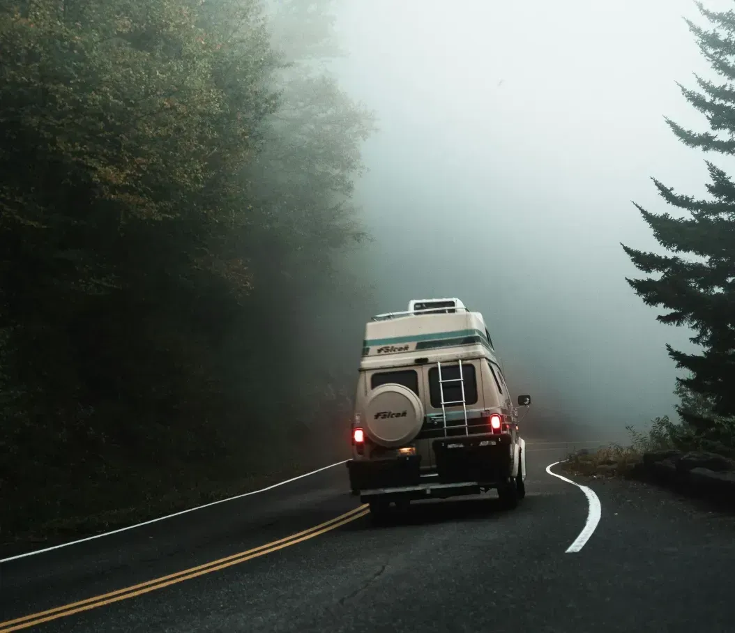 A car is driving down a foggy road.