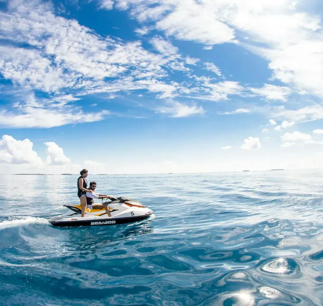Couples are riding a jet ski in the ocean.