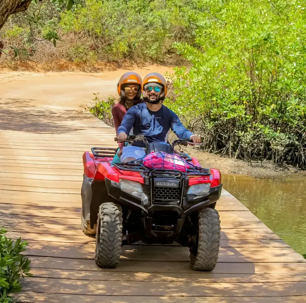 A man and a woman are riding an atv over a wooden bridge.