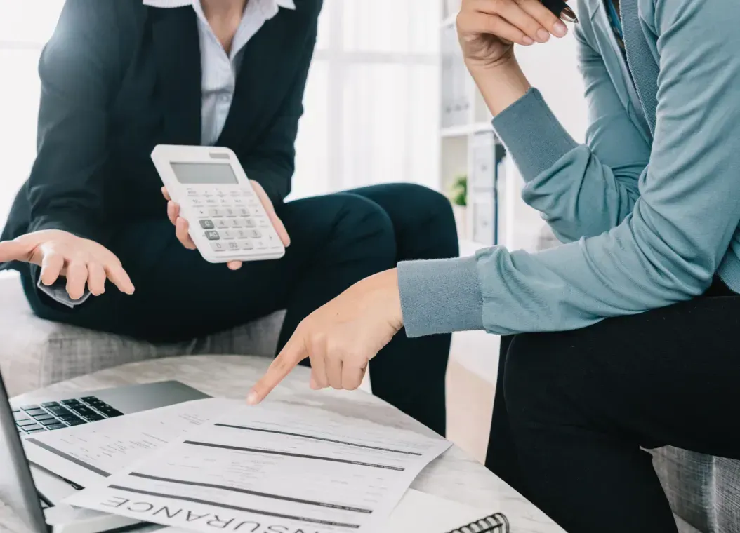 A man and a woman are sitting at a table with a laptop and a calculator.