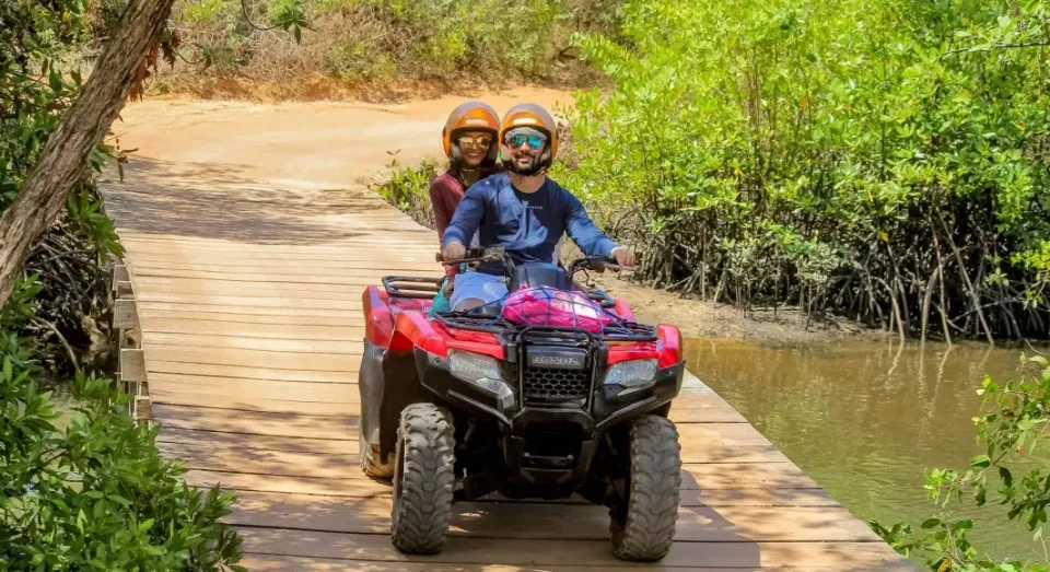 A man and a woman are riding an atv over a wooden bridge.
