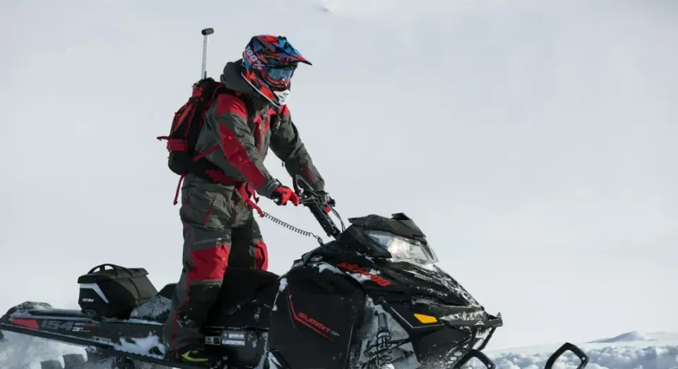 A man is riding a snowmobile in the snow.