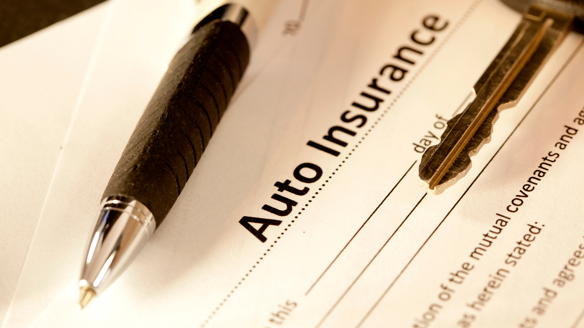A pen rests on top of an auto insurance form
