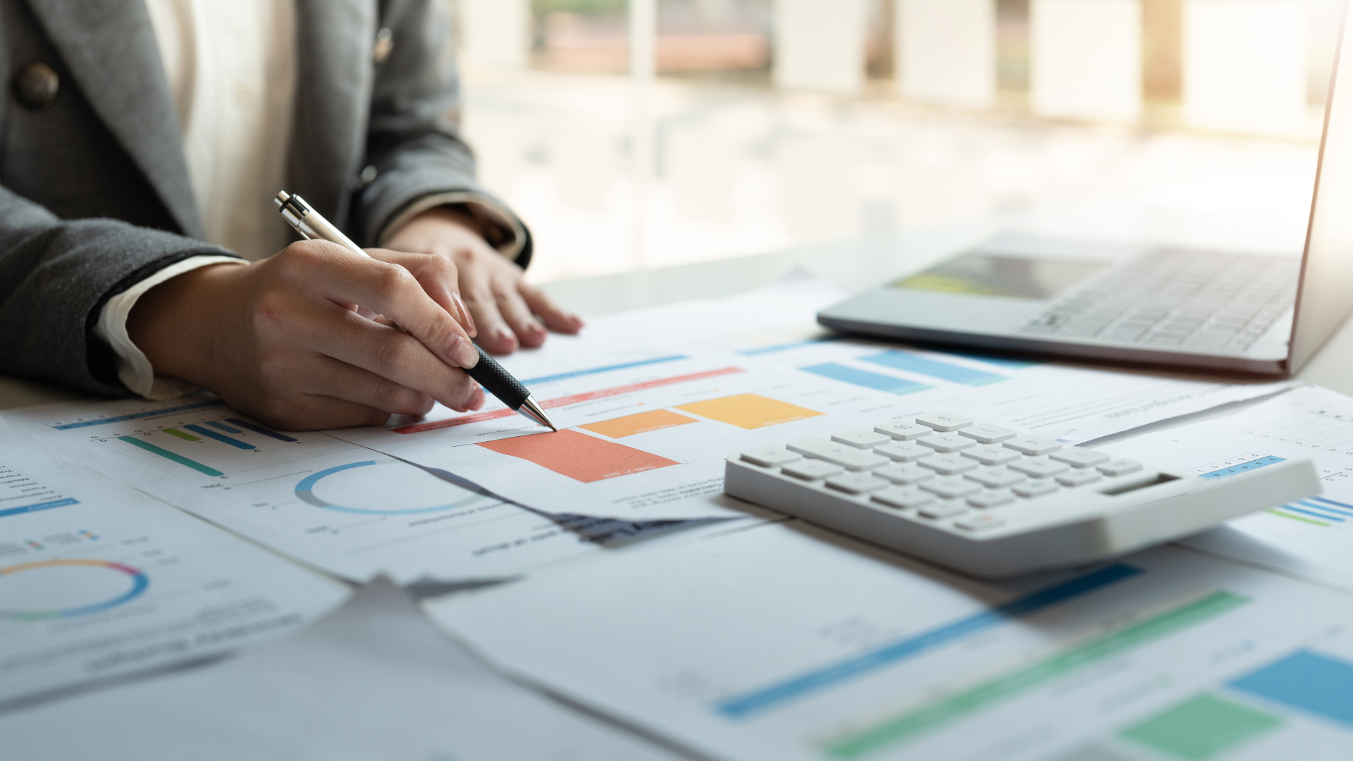 A woman is sitting at a desk with a pen and calculator.