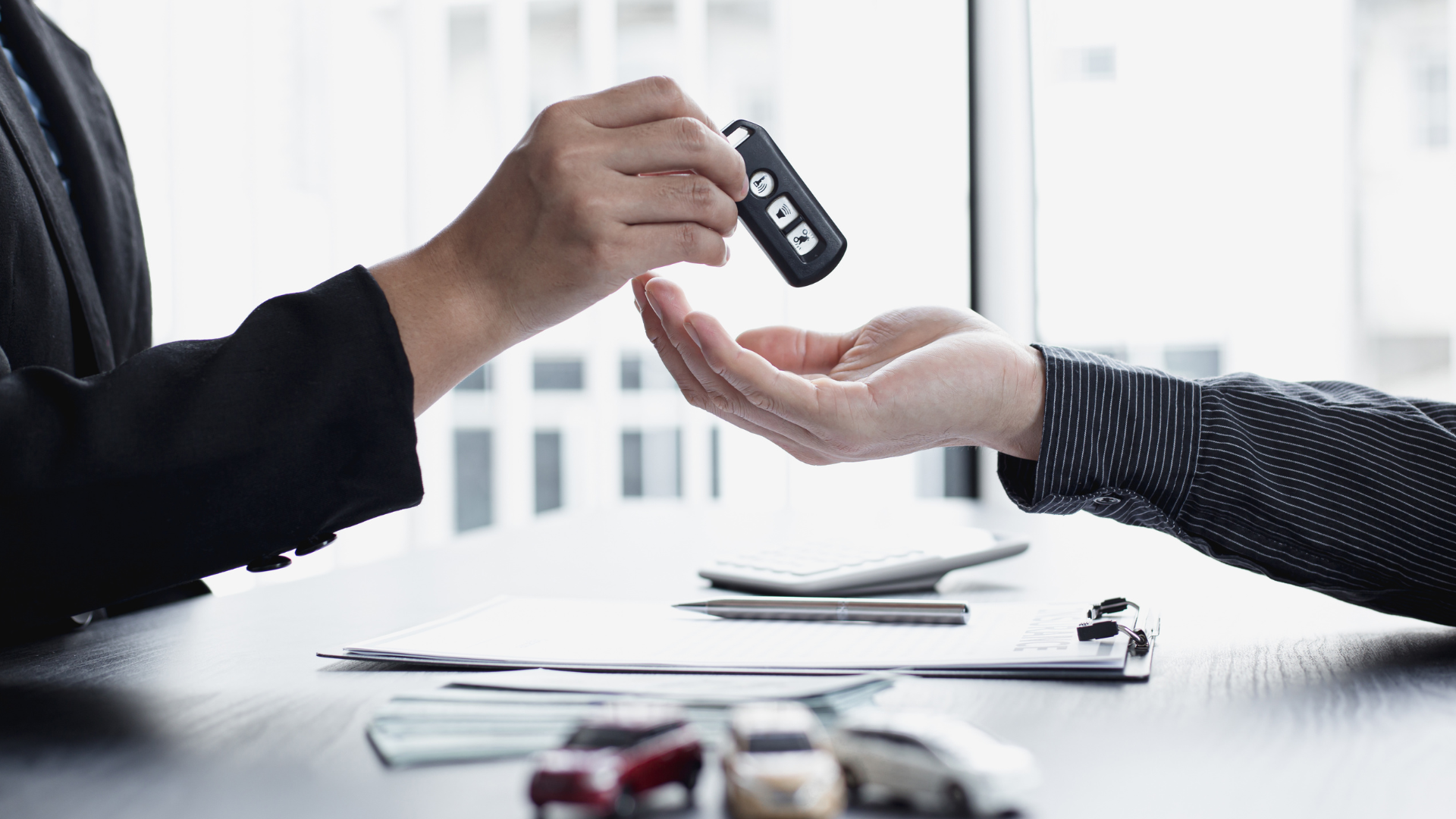 A woman is handing a car key to a man.