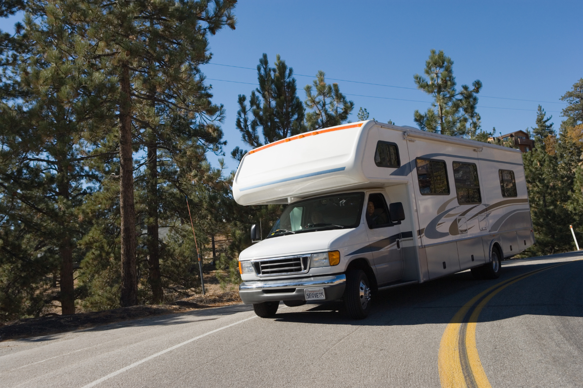 A white rv is driving down a curvy road.