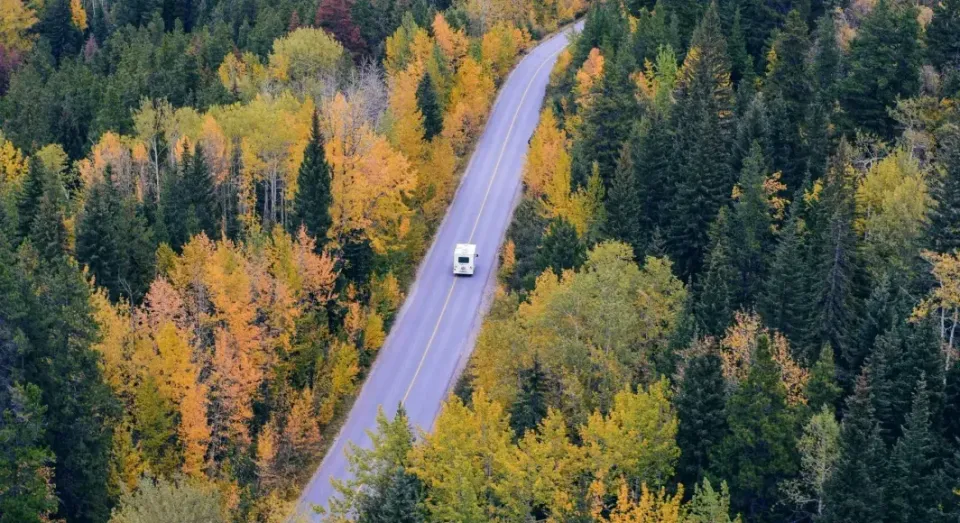 A blue atv is driving down a dirt road.