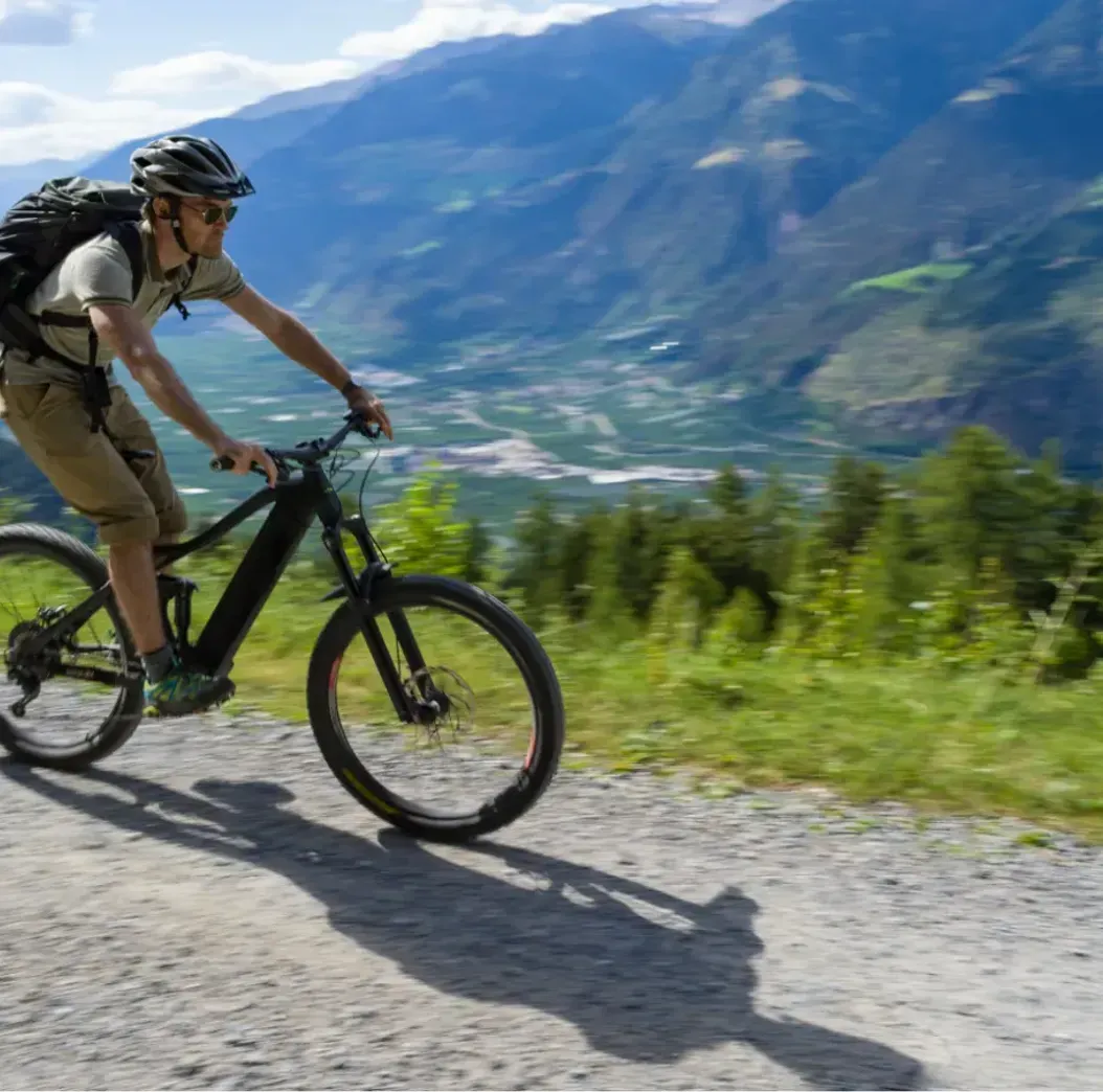 A man is riding an electric mountain bike on a dirt road.