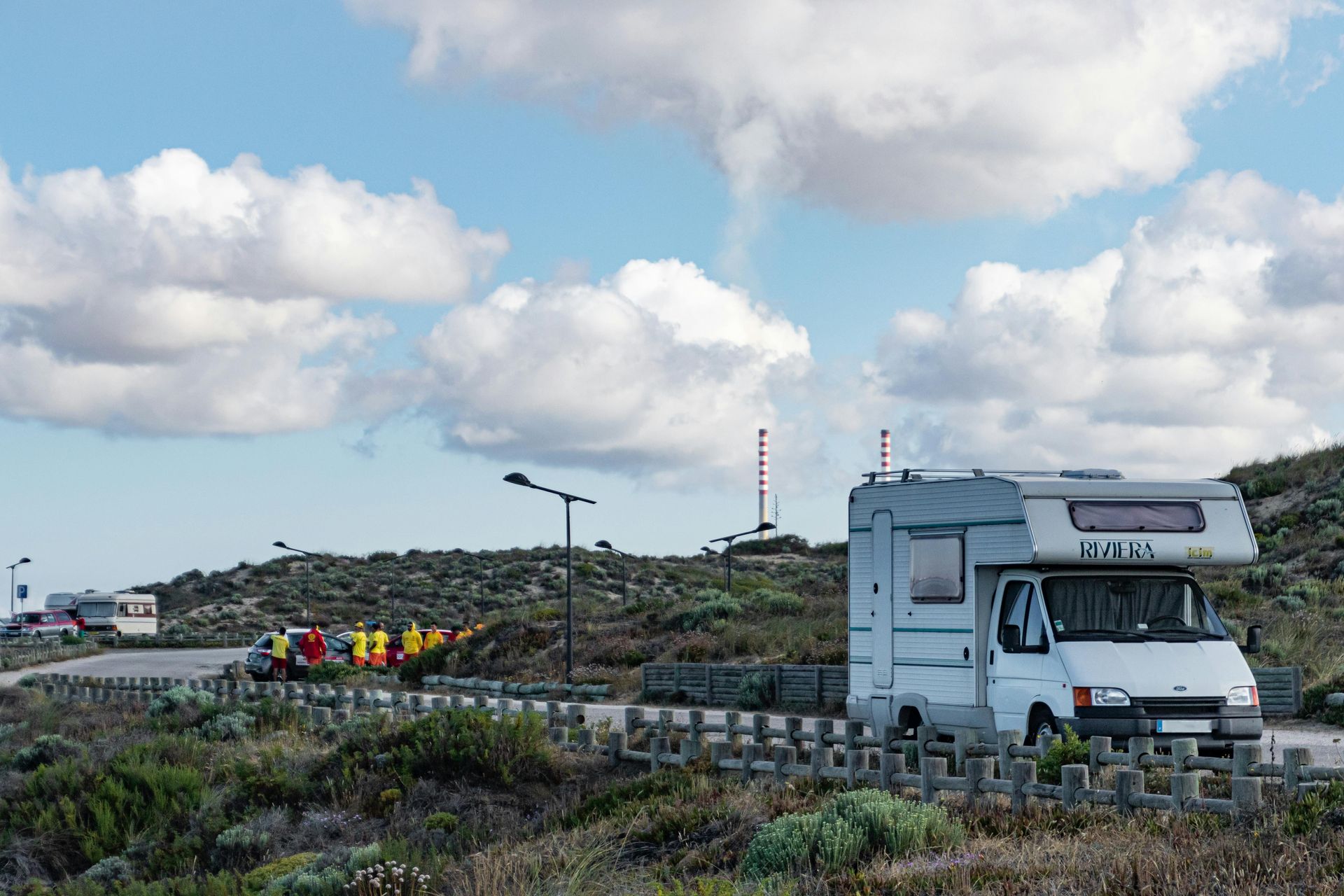 A white rv is parked on the side of the road in a field.