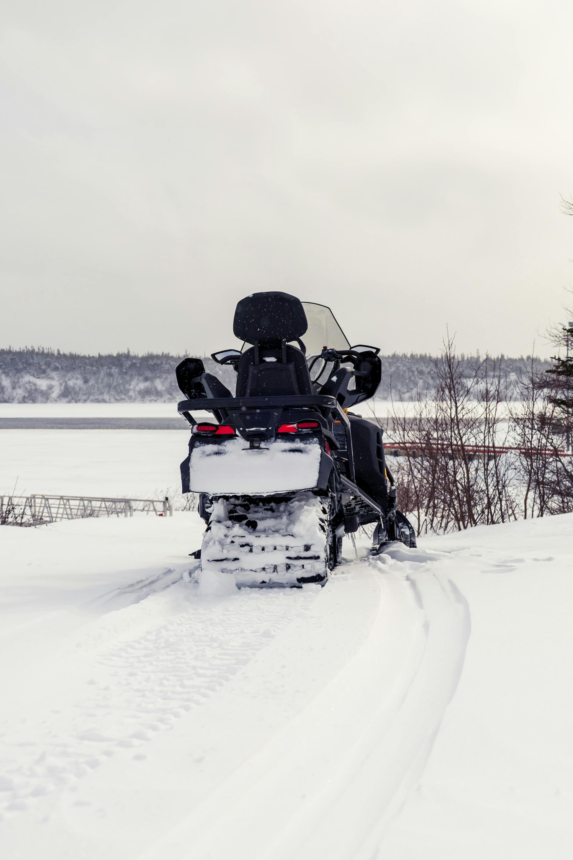 A snowmobile is driving down a snowy road.
