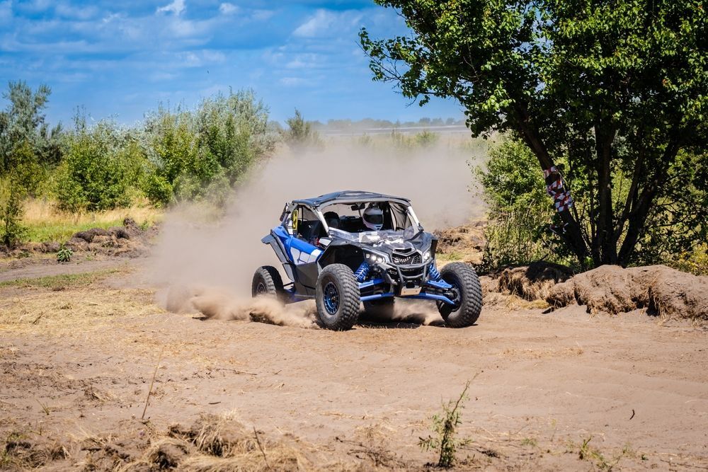 A blue atv is driving down a dirt road.