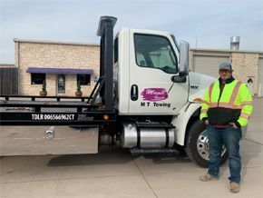 A man is standing in front of a tow truck.