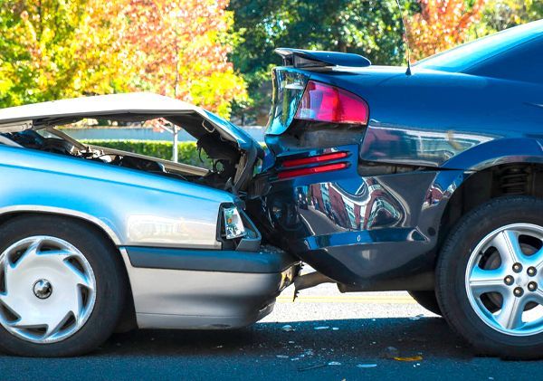 Two cars are involved in a car accident on the side of the road.