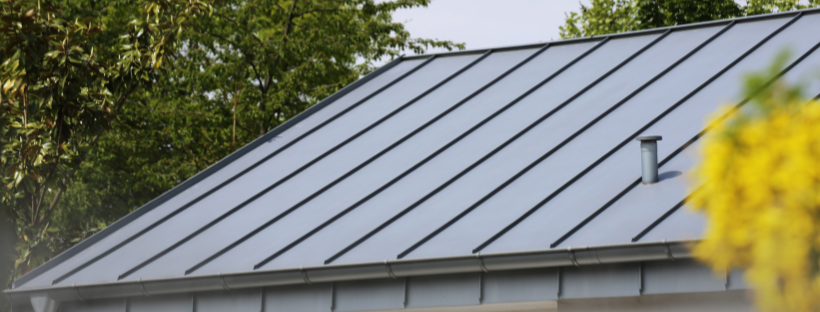A close up of a roof with a yellow flower in the foreground.