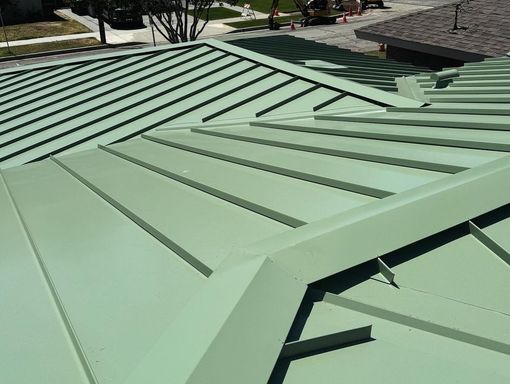 A green metal roof is being installed on a house.