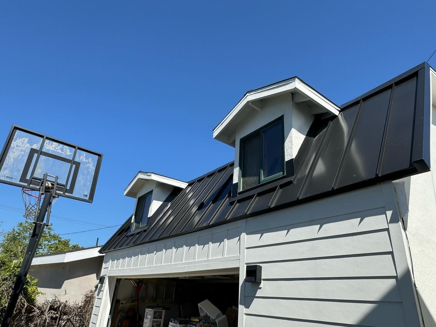 A basketball hoop is sitting on top of a garage next to a house.