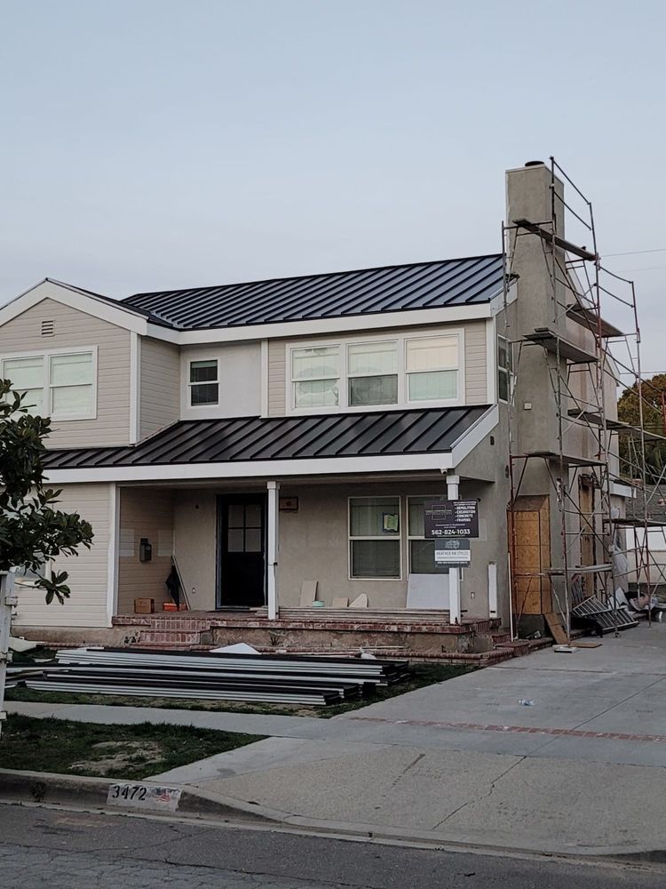 A white house with a black roof is under construction