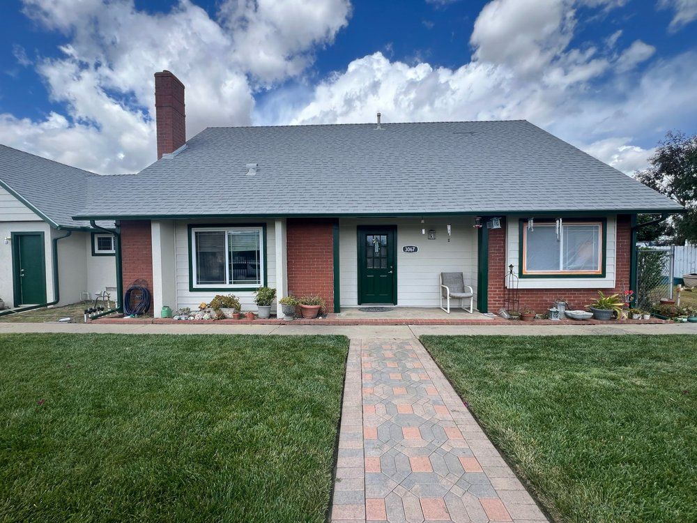 A brick house with a gray roof and a green door
