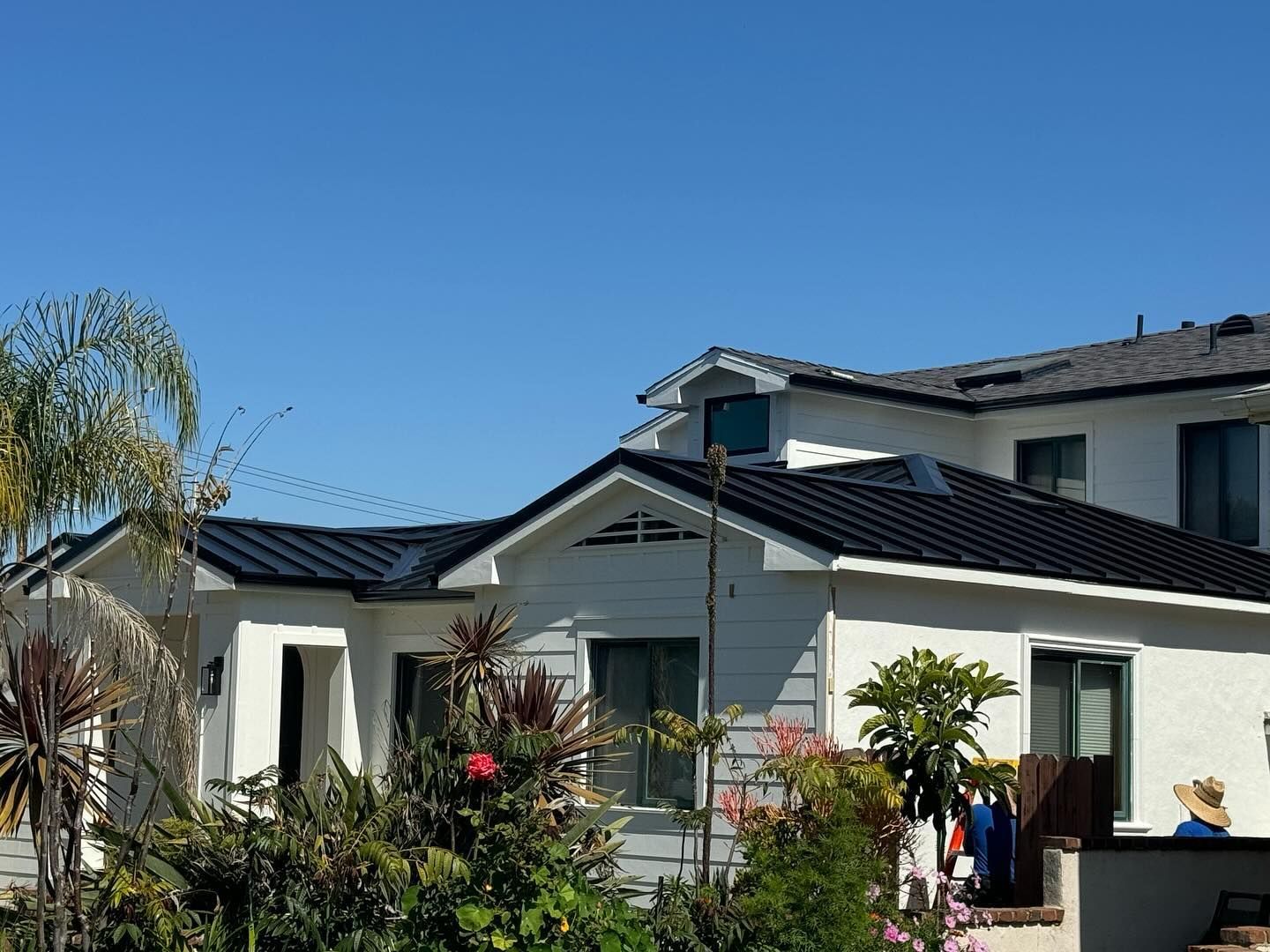 A white house with a black roof and a blue sky in the background