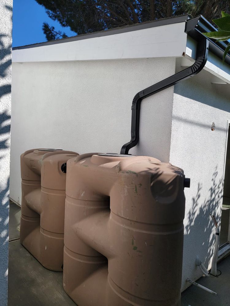 Two brown water tanks with a black drain pipe attached to them