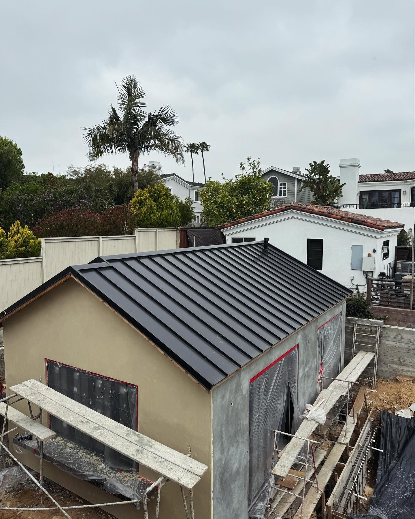A small house with a black roof is under construction