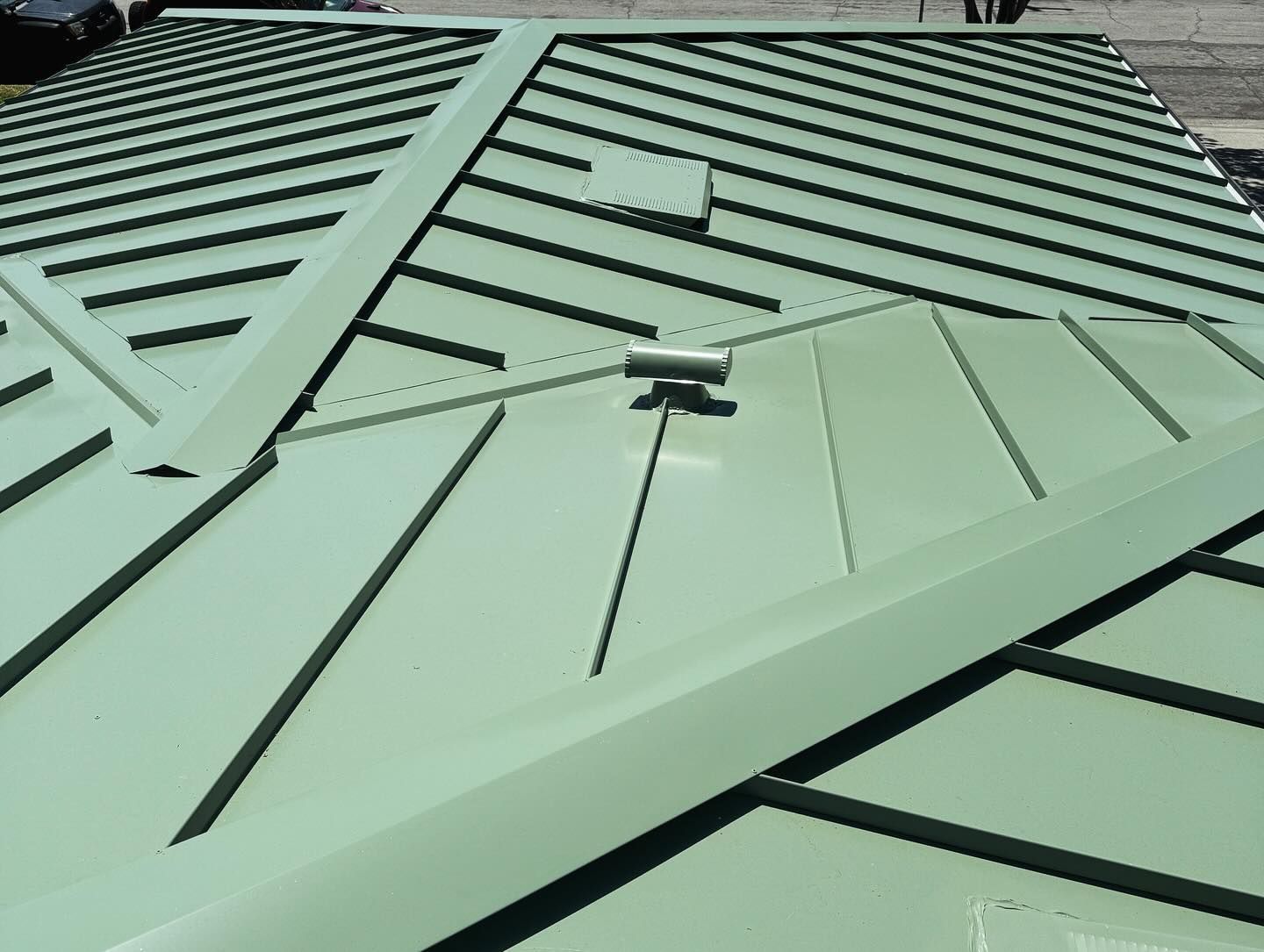 A close up of a green metal roof with a roof vent.