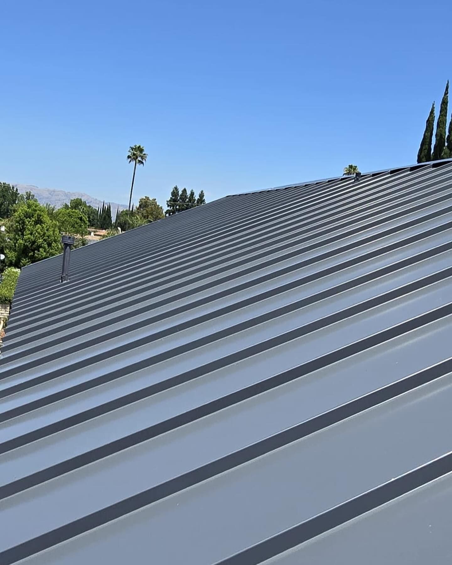A close up of a metal roof with a blue sky in the background.