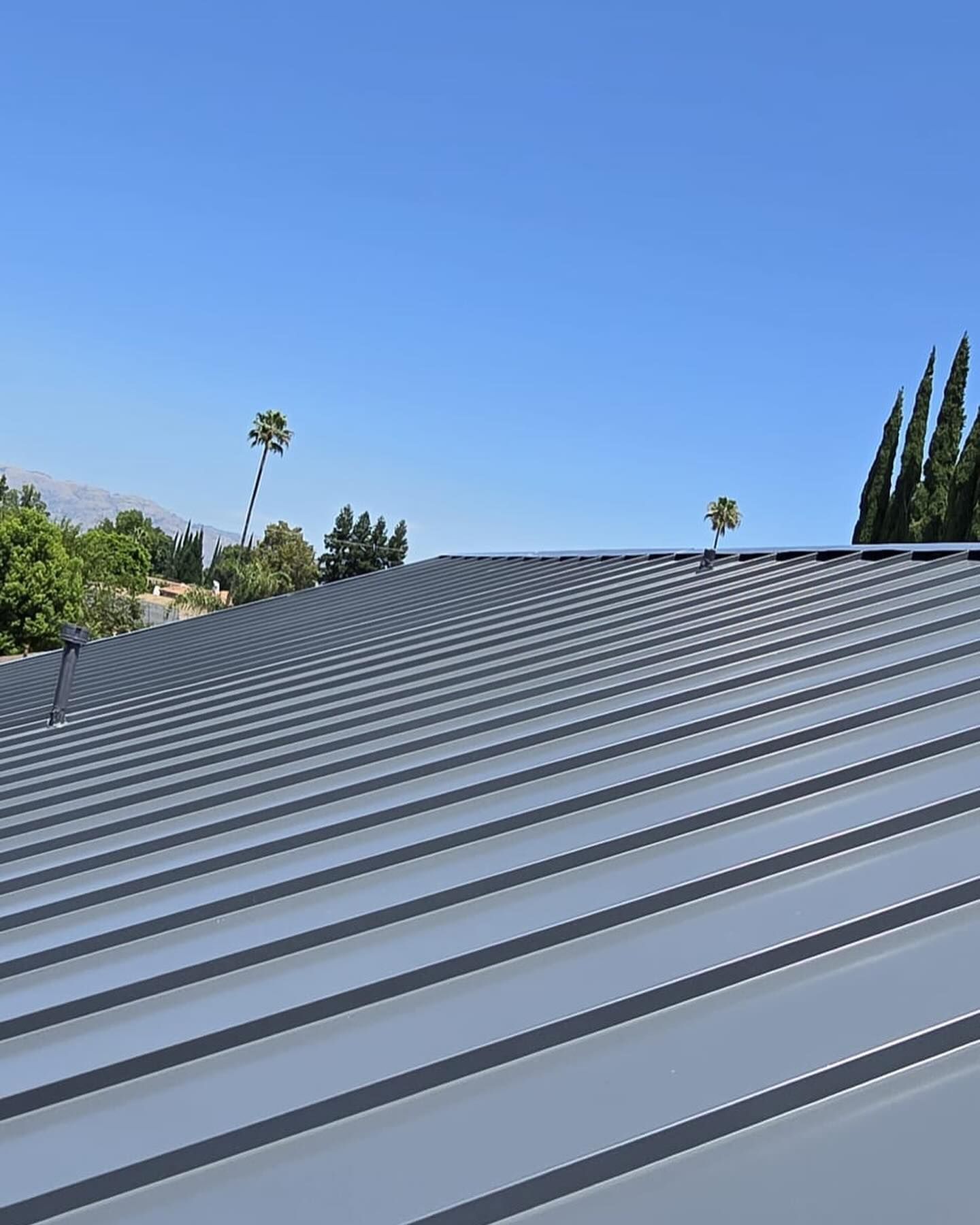 A close up of a metal roof with a blue sky in the background.