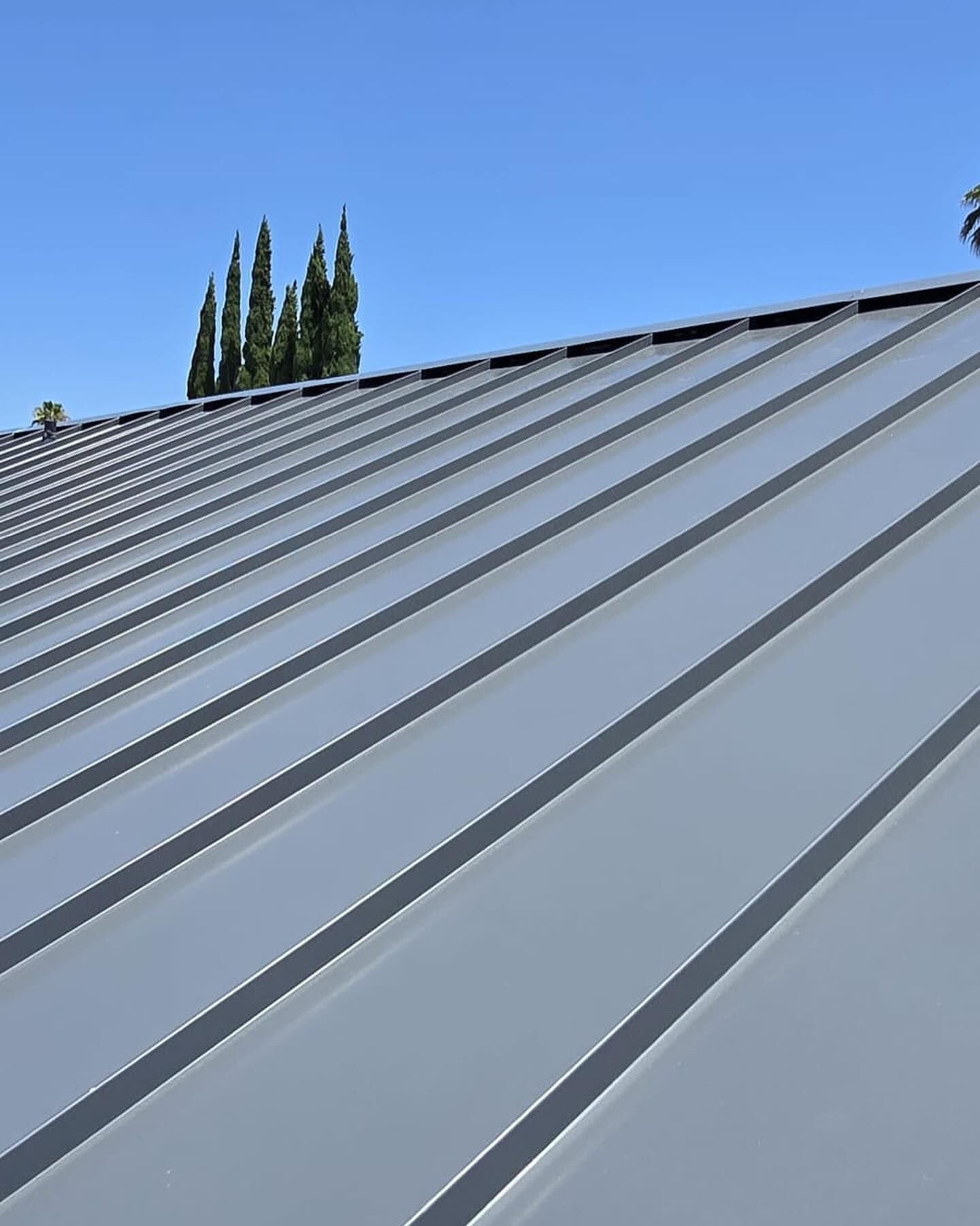 A close up of a metal roof with trees in the background.