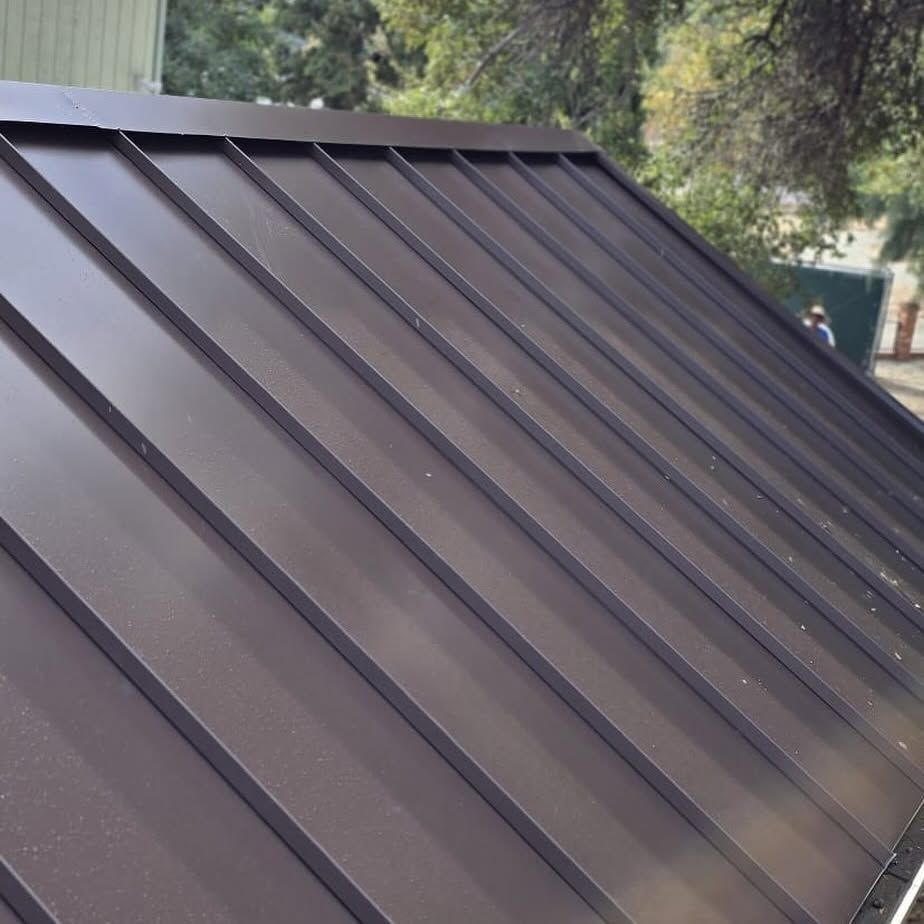 A close up of a brown metal roof with trees in the background