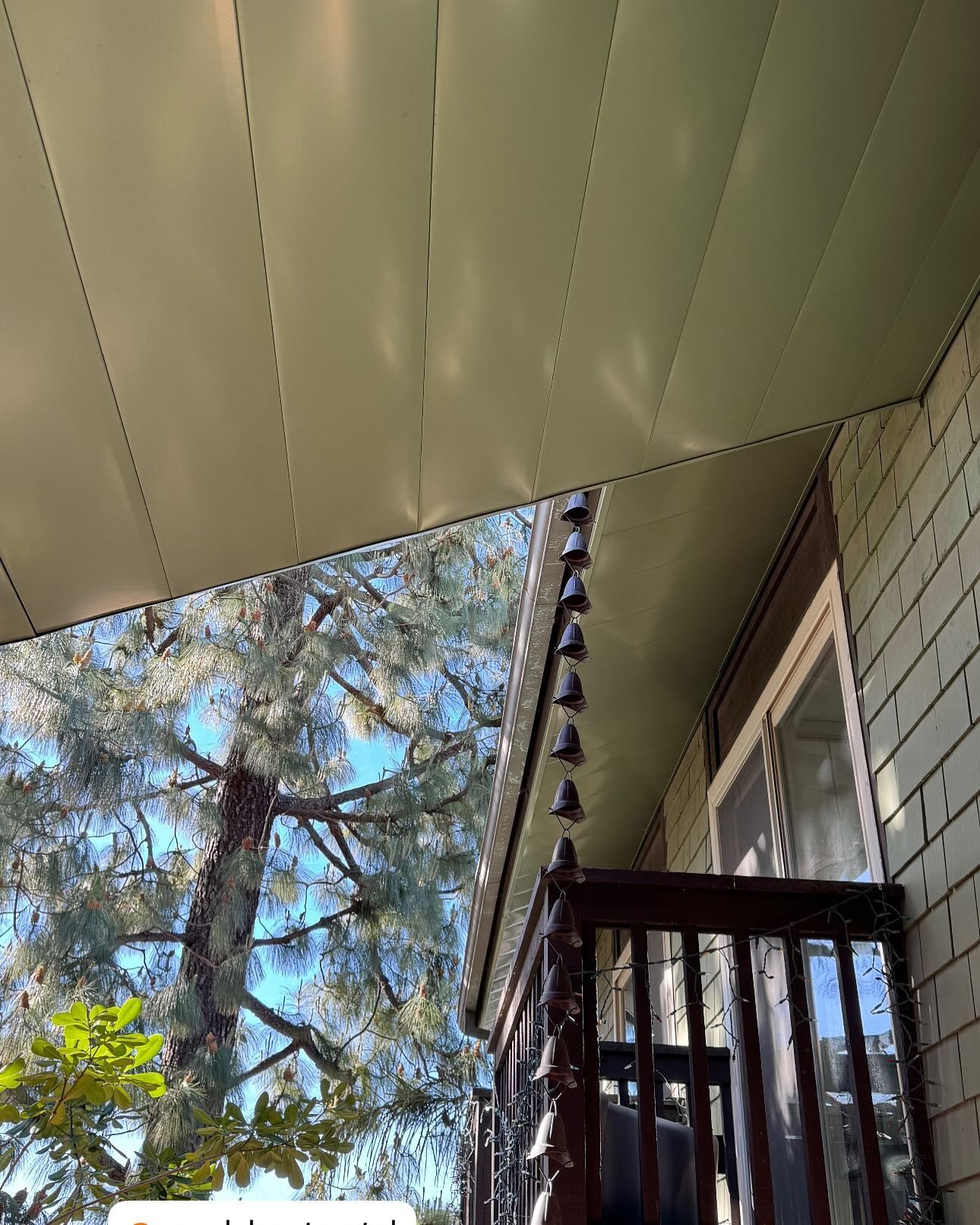 Looking up at the ceiling of a house with a balcony and trees in the background.