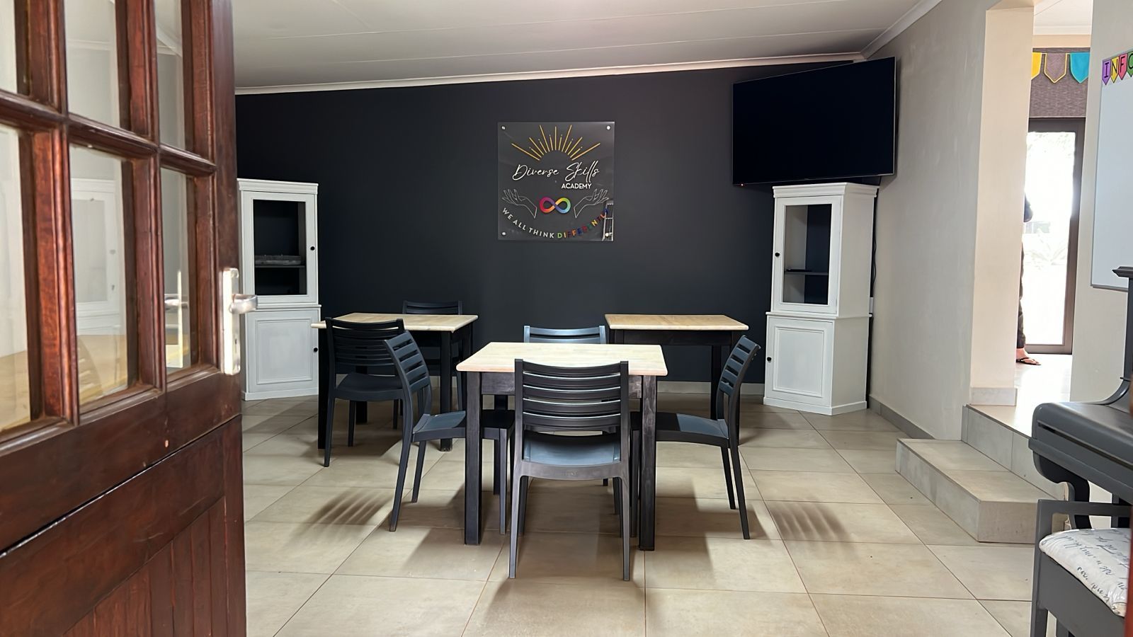 A room with tables and chairs and a television on the wall.