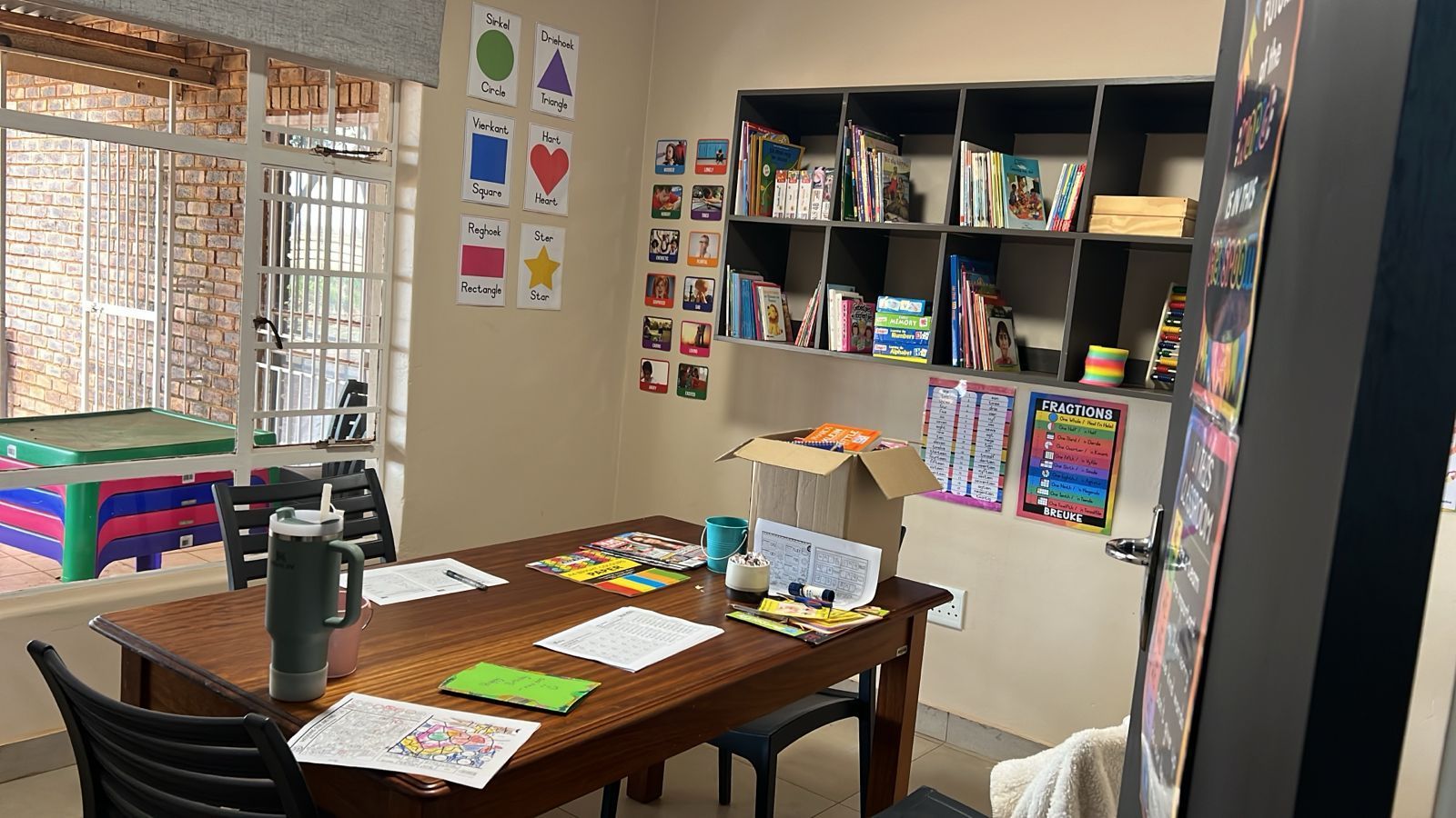 A room with a table and chairs and a bookshelf.