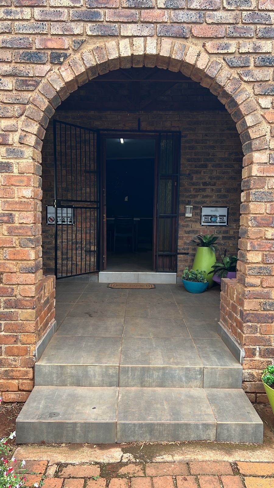 The front door of a brick house with a stone archway and steps leading up to it.