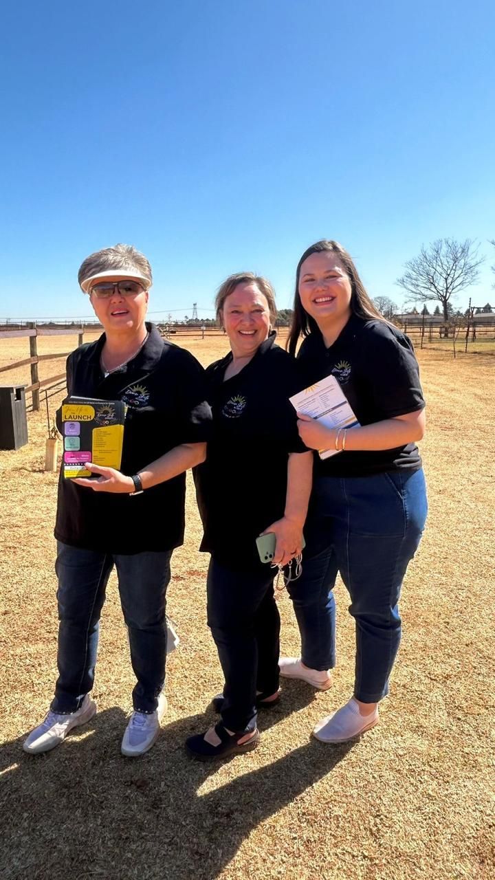 Three women are standing next to each other in a field.