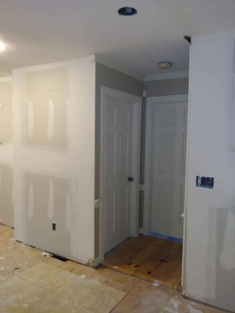 Interior view of a hallway under construction, with doors, drywall, and unfinished flooring.