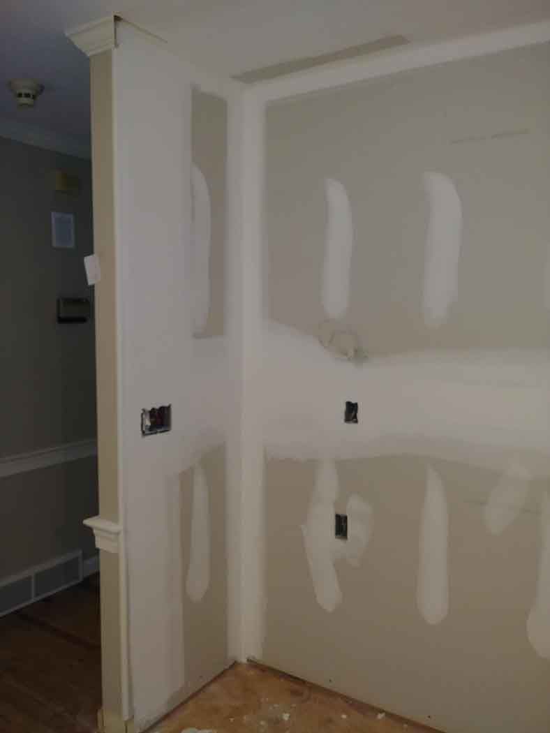 Corner of a room under construction with drywall and electrical outlets visible.
