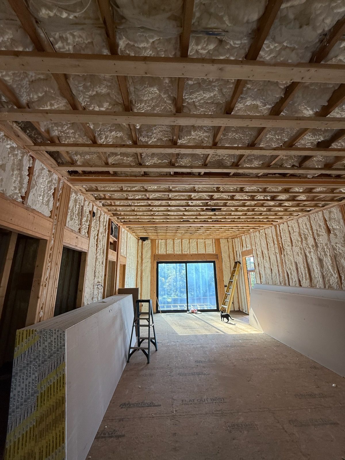 Wooden frame of a house under construction against a blue sky with clouds.