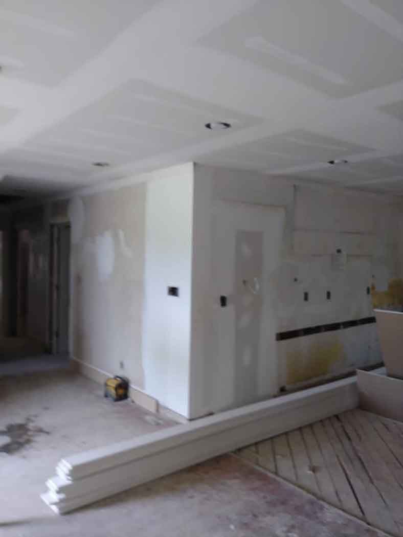 Interior room under construction with drywall, wood trim, and a doorway.