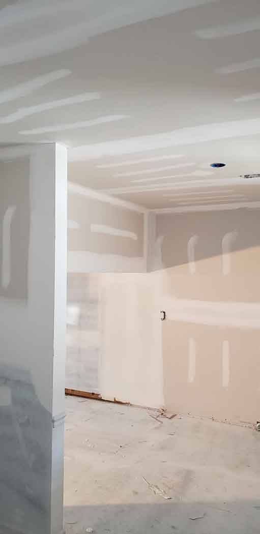 Interior view of a room under construction with exposed drywall and unfinished concrete floor.