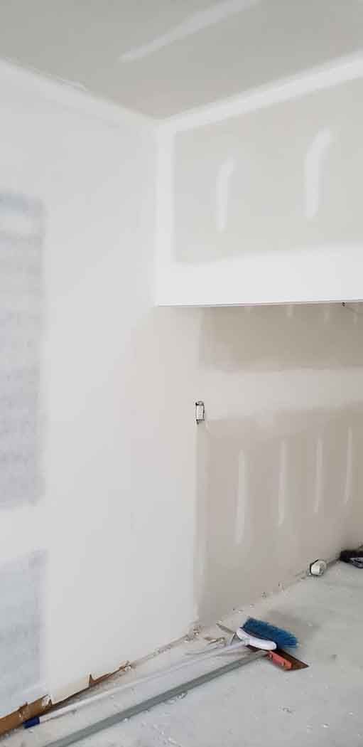 Interior corner of a room under construction with drywall and unfinished walls.