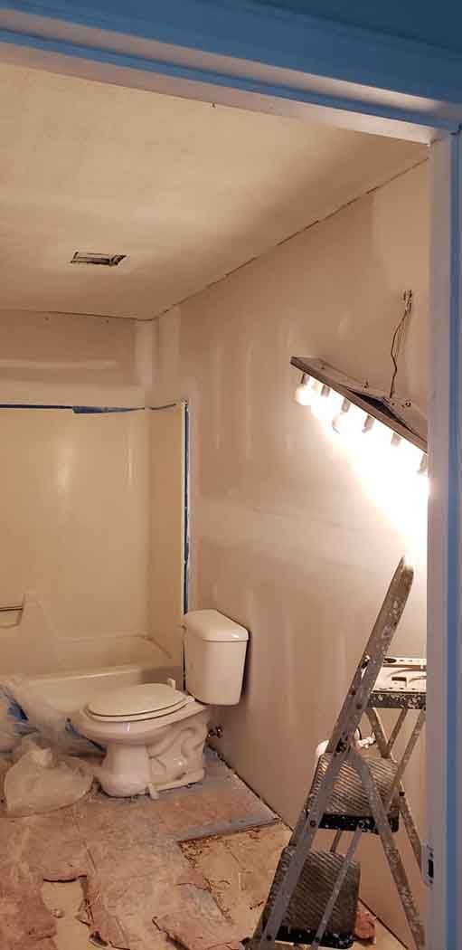 Bathroom under construction with toilet, shower, and a stepladder.