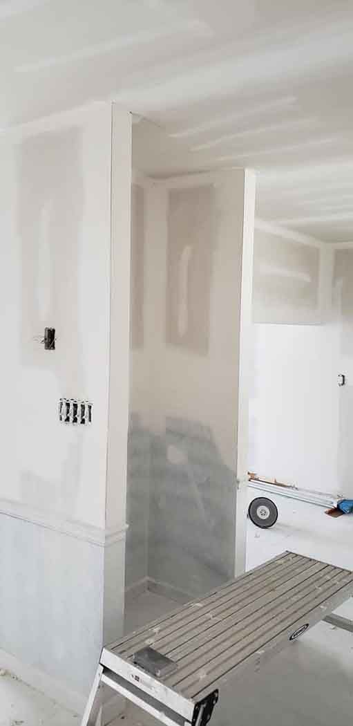 Interior view of a room under construction with exposed drywall and a step ladder.