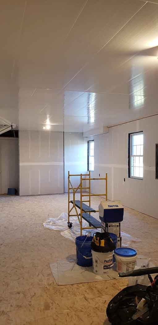 Interior of a room under construction with scaffolding, buckets, and unfinished walls.