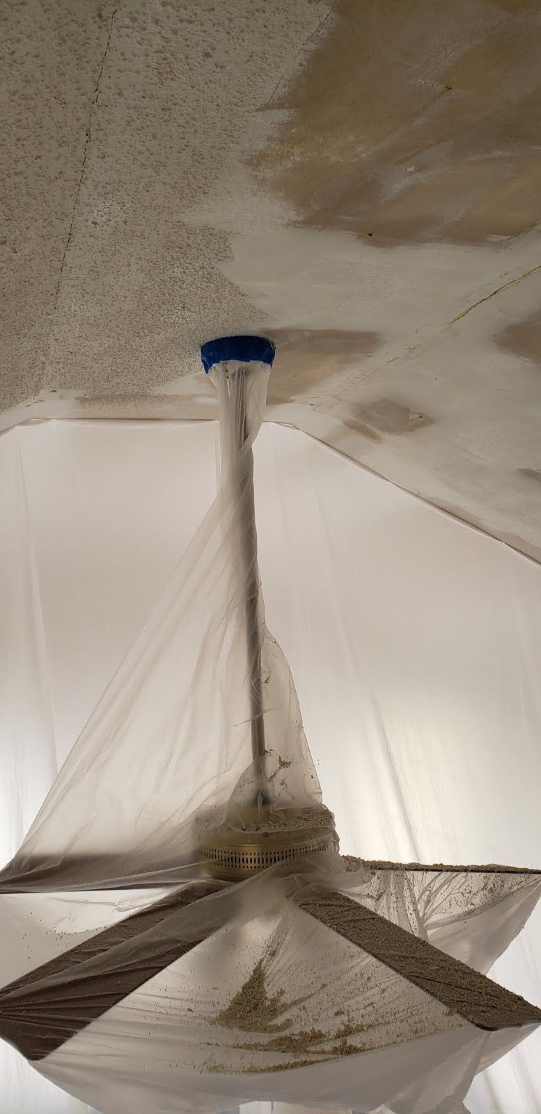 Ceiling fan covered in plastic sheeting for dust containment, likely during a renovation.