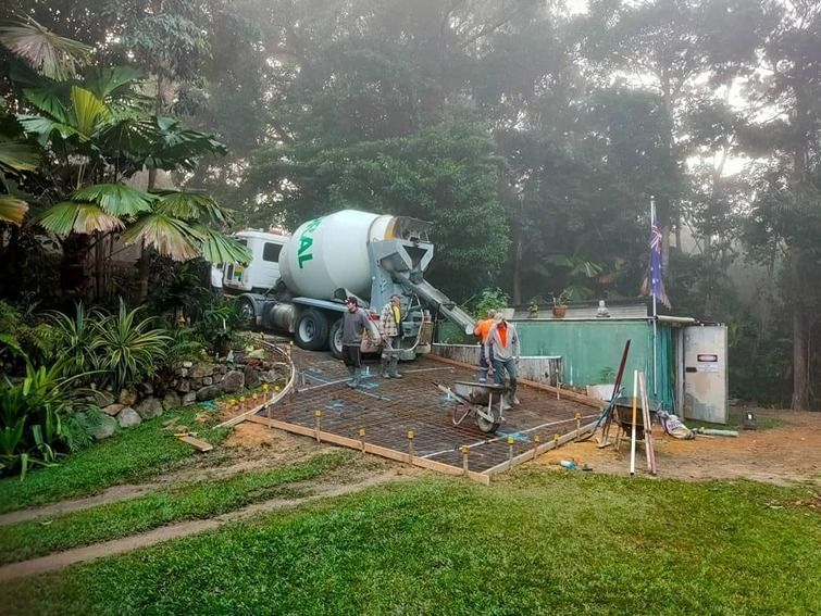 A Concrete Mixer Truck Is Pouring Concrete Into A Yard — B & C Donnachie Concrete Contractors in Kuranda, QLD